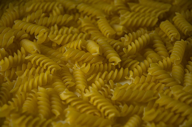 A detailed close-up image of raw yellow spiral pasta, showcasing texture and pattern, perfect for food-related designs.