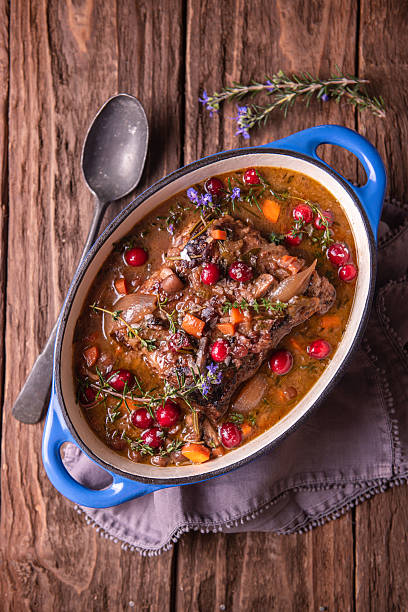 Braised Beef Stew with Fresh Cranberries in Blue Dutch Oven on Rustic Wooden Table