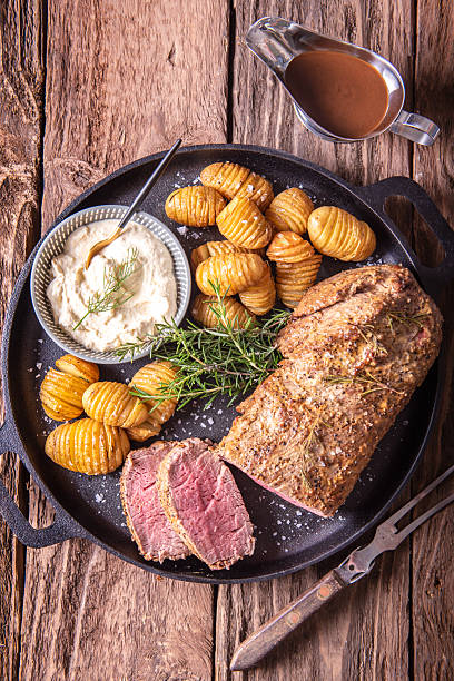 Roast Beef Dinner With Hasselback Potatoes, Horseradish Sauce and Gravy on Cast Iron Pan