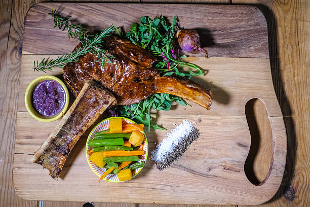 Roasted Beef Rib With Bone Marrow, Seasonal Vegetables and Sauce on Wooden Cutting Board