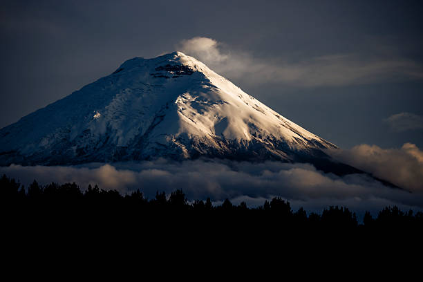 Majestic Chimborazo volcano partially covered by clouds during a breathtaking sunset, creating a stunning landscape in the Ecuadorian Andes