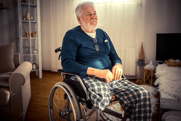 Lonely senior man sitting in a wheelchair, gazing at the distant horizon on a cloudy day, surrounded by the tranquil atmosphere of a retirement home garden