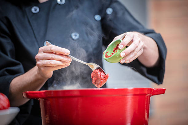 Horizontal angled shot of a blue pot on a stove top holding hearty tomato soup that is simmering.
