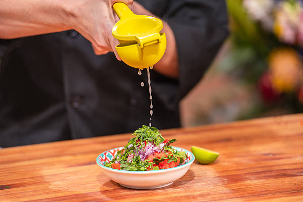Chef Squeezing Lime Over Fresh Tomato Salsa Bowl on Wooden Countertop, Close-Up Food Prep