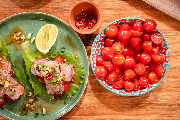 Grilled Steak Lettuce Wraps With Cherry Tomatoes, Lime and Chili on Wooden Table