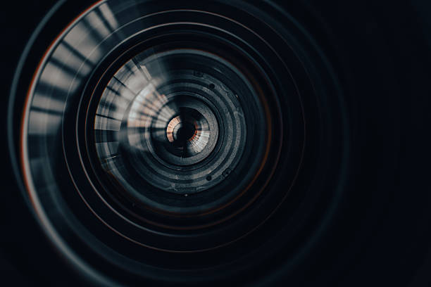 A mesmerizing macro shot peering into the complex internal elements and glass coatings of a high-end camera lens, showcasing radial symmetry, reflections, and precision optical engineering.