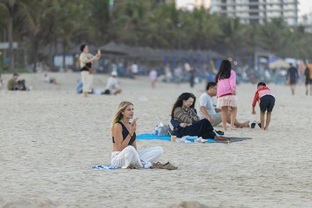 14 February 2026, Da Nang - Vietnam.A tourist rests on the sandy shoreline, enjoying the coastal environment and sea breeze. Da Nang’s beaches are known for their clean sand and open space.