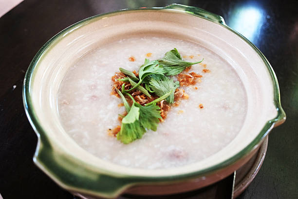 Rice porridge machine served in a white bowl with minced pork and coriander and fried garlic sprinkled on top