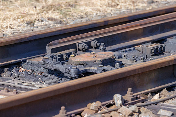 A close-up of the switching mechanism near a railway turnout (point). Heavy black grease is applied to prevent wear on moving parts and ensure smooth operation. Mechanical elements such as bolts, nuts, and cotter pins, along with the texture of maintained iron, tell the story of railway infrastructure safety.