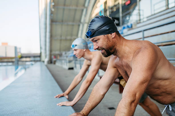 Butterfly swimming technique. Young muscular man, professional swimmer in goggles training at public swimming-pool, outdoors. Sport, power, energy, style, hobby concept. Celestial blue water