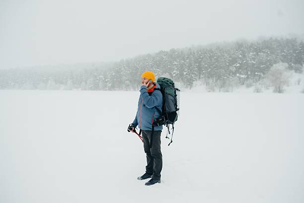 A mountaineer with a backpack on his back and in a ski jacket enjoys a cold winter day. ISL