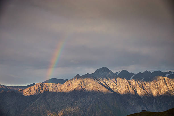 Climbing Mount Kazbek. Rainbow appears over mountain range during early evening hours with clouds in the sky
