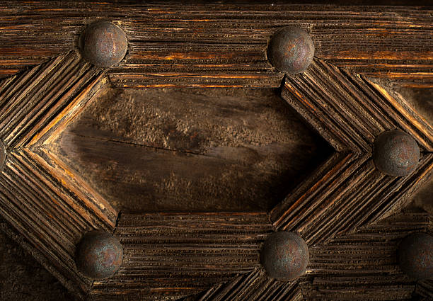Close-up of intricate wooden carving with symmetrical geometric pattern. Rich texture and deep shadows highlight craftsmanship and antique aesthetic..
