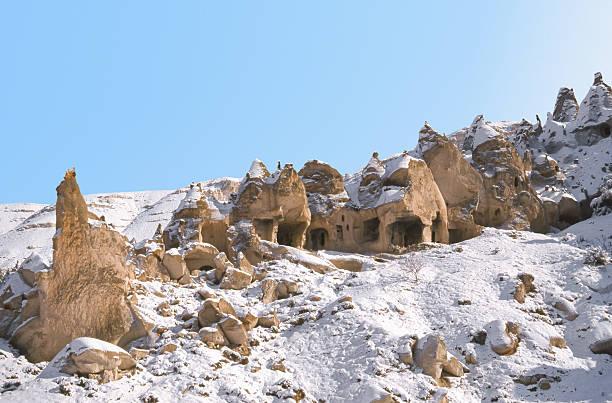 Young woman walking among rocks in Capadocia, wearing a red dress.