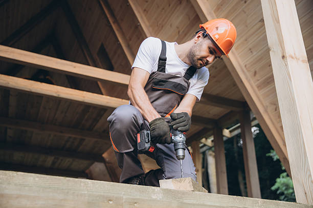 Construction worker working with screwdriver on wooden frame, diy eco-friendly homes concept. Man using drill working on construction of wood modular house