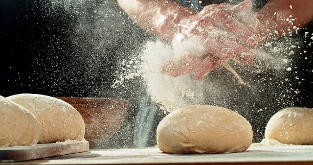 Chef Clapping Flour-Covered Hands. Flour Explosion During Yeast Dough Preparation, Baking Concept on Dark Background