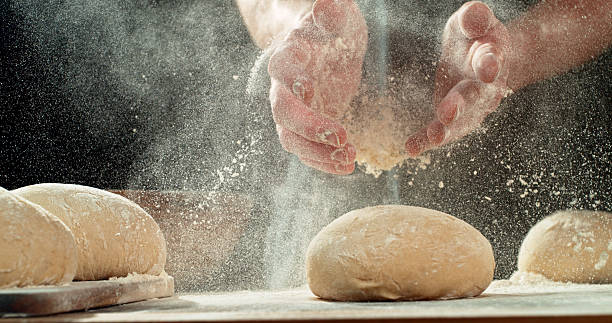 Chef Clapping Flour-Covered Hands. Flour Explosion During Yeast Dough Preparation, Baking Concept on Dark Background