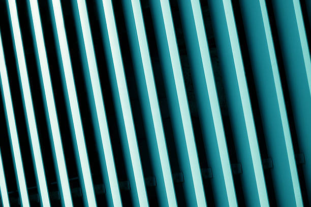 A close-up, abstract view of parallel teal and black lines angled diagonally, forming a striking geometric pattern with strong contrast and shadow