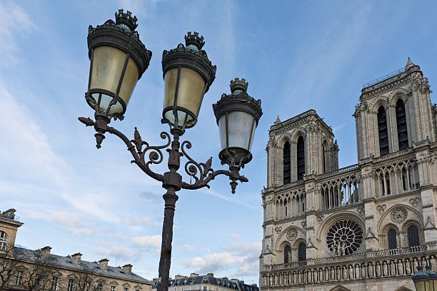 This image captures an iconic Paris pairing: a historic three-headed wrought-iron streetlamp in the foreground and the majestic western façade of Notre-Dame Cathedral rising behind it.