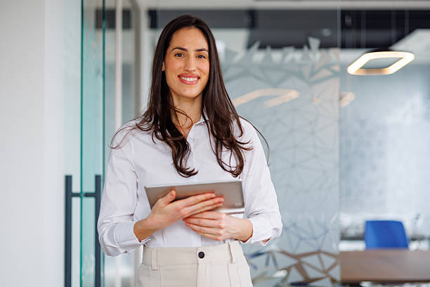 istock Confident businesswoman smiling, holding a digital tablet in a modern office workplace setting 2261770236