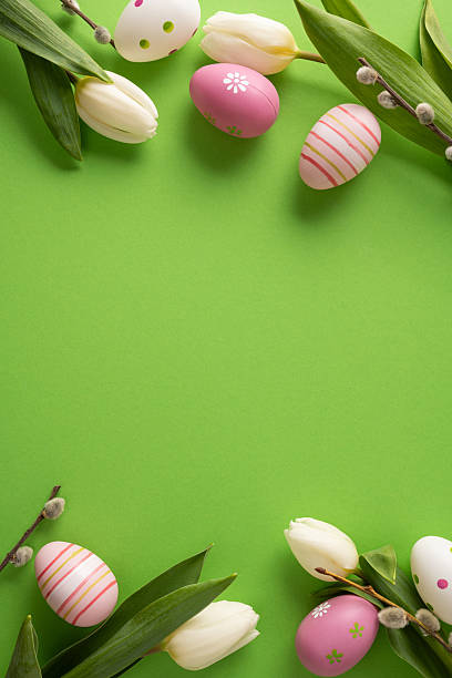 Colorful vertical Easter eggs, white tulips, and pussy willows create a festive spring frame. Bright green background sets a celebratory mood for Easter greetings and seasonal decor