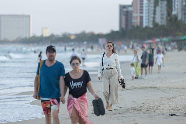15 February 2026, Da Nang Beach - Vietnam.Visitors stroll near the shoreline, where the waves meet the sand. Walking by the sea is a common activity along Da Nang’s long beaches, especially during the cooler hours of the day. The open coastline and gentle slope of the beach make it suitable for casual seaside walks.