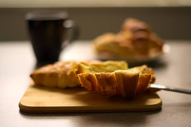 Croissants on a cutting board with cup of hot tea.