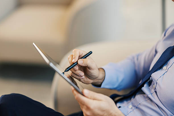 Mid adult businessman focusing on work using a digital tablet and stylus, representing modern technology and paperless solutions in the corporate world