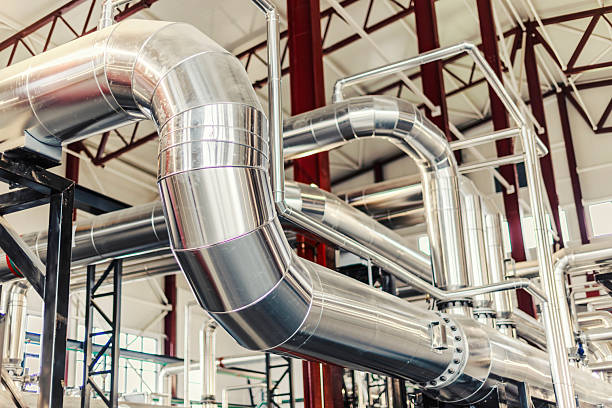 Stainless steel piping system running through a modern industrial facility, conveying fluids or gases for various manufacturing processes and energy production