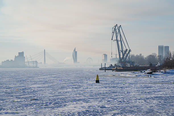 Frozen Daugava River on a winter morning and port cranes