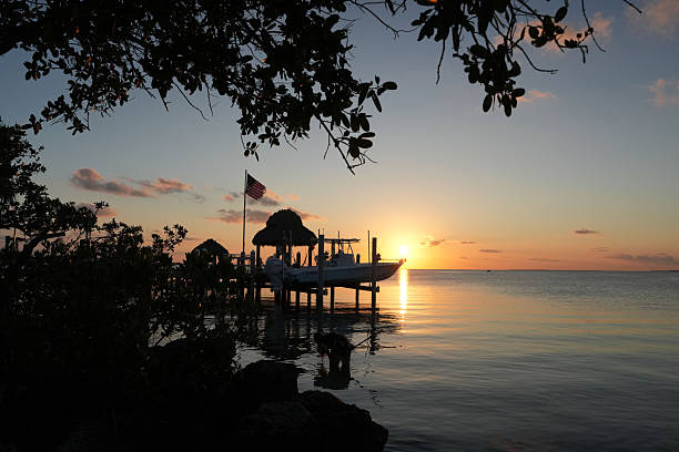Wide angle view of a sail boat sailing towards Sunset Key at sunset from Mallory Square, Key West, Florida.