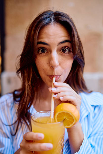 Young woman enjoying refreshing orange juice with wide eyes