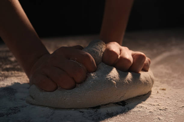 Making bread. Woman kneading dough at table, closeup