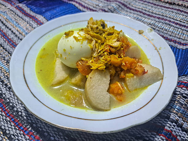 Lontong Opor Ayam or compressed rice cake with chicken curry in coconut milk with Sambal Goreng Kentang or fried potato chili sauce, shredded chicken and boiled egg. Indonesia Food Menu.