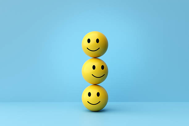 Yellow emoticon face balls stacking in a column, representing happiness, positive emotions, customer satisfaction, and mental well-being