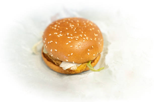 Sesame seed burger with chicken patty and lettuce on white paper background