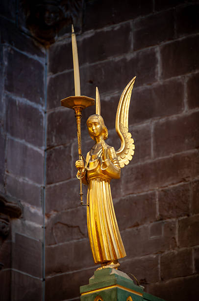 Bronze statuettes of angels on a display with drapery in the background.