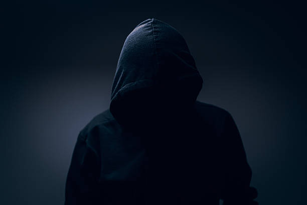 istock Dark hooded silhouette emerging from shadows, anonymous and enigmatic portrait symbolizing mystery, secrecy, tension, and the unknown. 2261926207