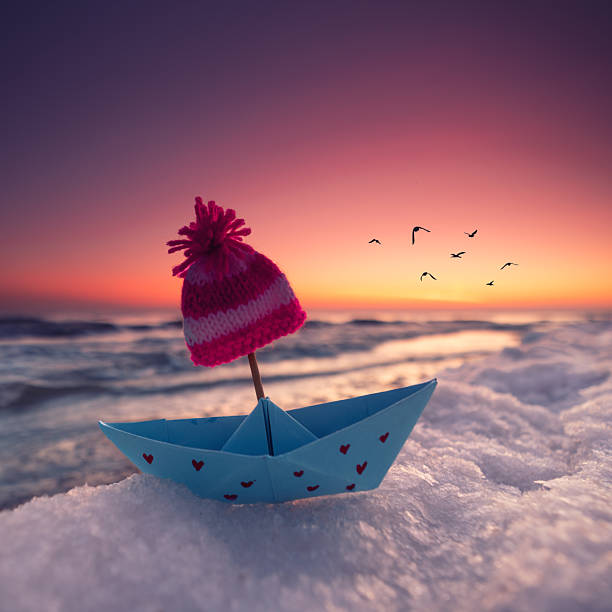 istock romantic paper boat with knitted hat in winter on the beach 2261946217