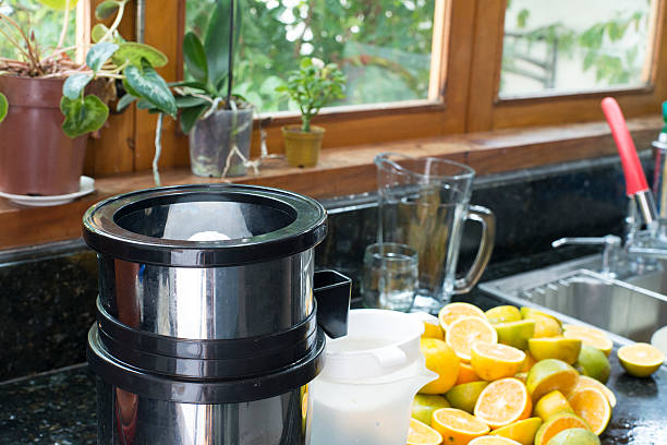 Close-up of a fruit juicer surrounded by fresh oranges cut in half, ready to be squeezed. The image highlights the artisanal preparation of natural juice, symbolizing a healthy diet, rich in vitamins and full of energy for daily life.