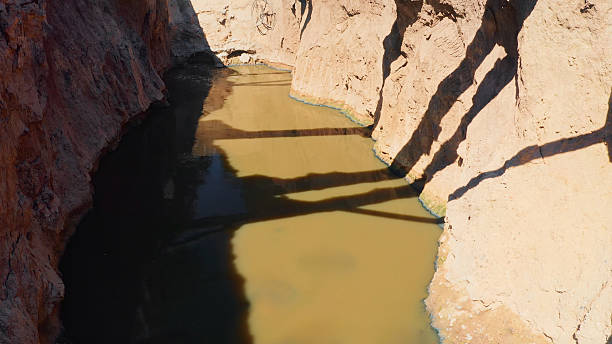 Dirty water filling a narrow desert canyon, showing environmental pollution and erosion