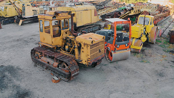 Heavy construction machinery and road rollers parked in an outdoor industrial junkyard