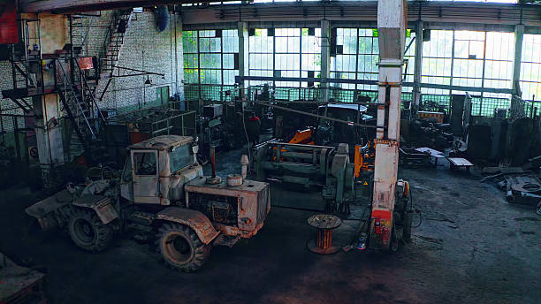 Large abandoned machine shop full of old tractors and heavy equipment standing idle