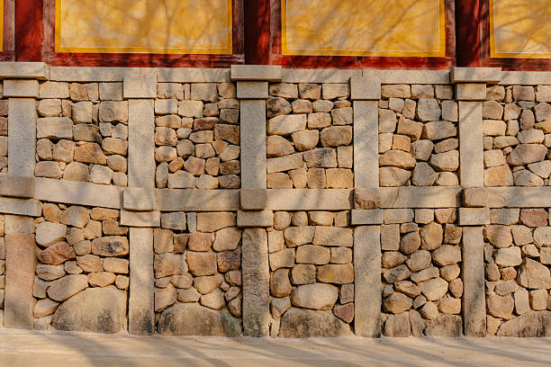 An old weathered stone wall with its unique architectural design, enhanced by sunlight and soft shadows. Part of ancient building.