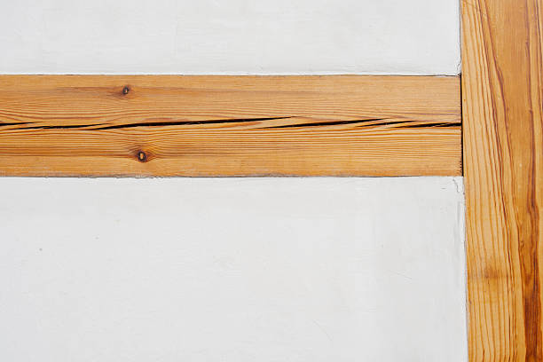 Close-up shot displaying a wall with bright white paint, accented by a horizontal wooden board that's cracked.