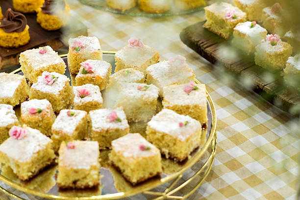 Small cake slices and assorted sweets arranged on a checkered tablecloth in a clean and minimalist environment, representing homemade baking, dessert presentation, and cozy atmosphere.