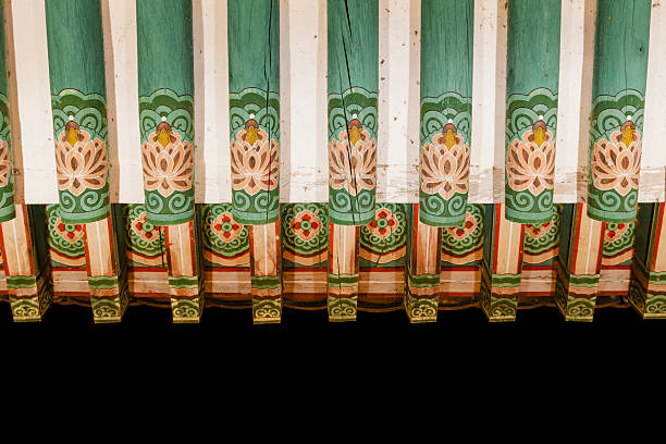 This is a view of an aged building featuring green painted pillars and lotus decorations, set against the backdrop of a black sky.