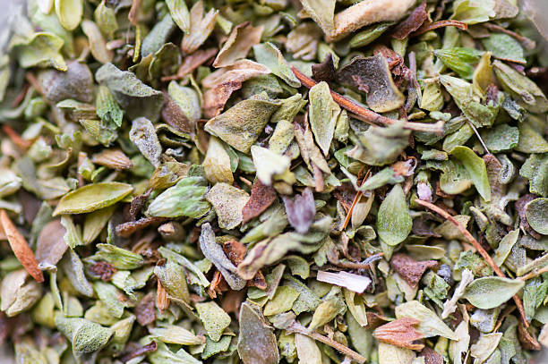Top view of dried oregano leaves creating natural green texture, culinary herb background.