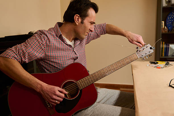 Senior man a veteran guitarist clean and repair the old electric guitar at home
