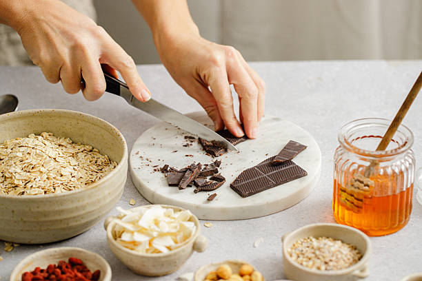 Hands chopping dark chocolate for healthy breakfast preparation